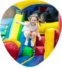 A young girl wearing a striped dress is jumping on a colorful inflatable bounce house, enjoying nonstop Bouncy House Fun.