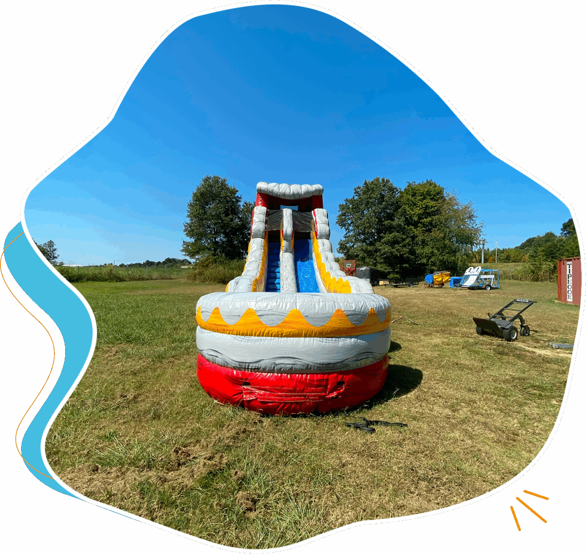 A colorful inflatable slide set up in a sunny, grassy outdoor area.