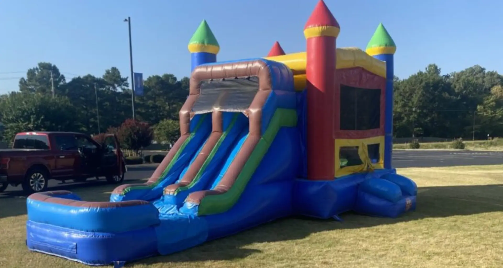 Colorful inflatable bounce house with dual slides outdoors.